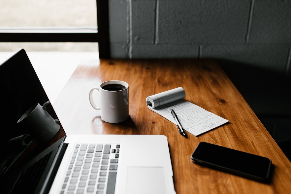 Laptop on the table with coffee mug, notebook and phone - Koofr blog