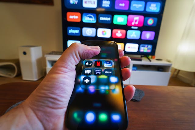 A hand holding a phone displaying streaming apps