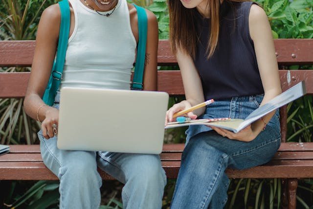 Crop faceless diverse students preparing for exam together in park