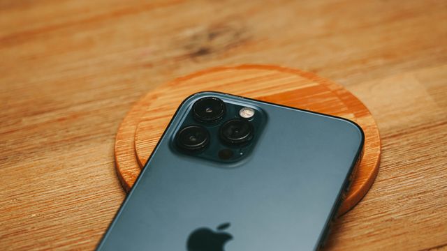 Detailed close-up of a modern smartphone camera on a textured wooden surface
