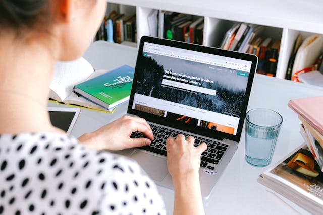 Person Using Macbook Pro On White Table with a Glass of Water.jpg