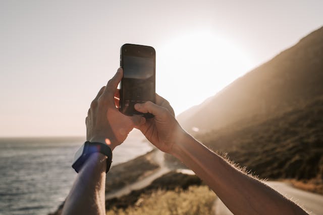 Person taking a photo of the sunset over the coastline with a smartphone.jpg