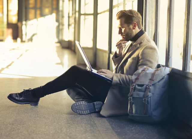 Young man sitting indoors at an airport using laptop. Ideal for remote work themes.jpg
