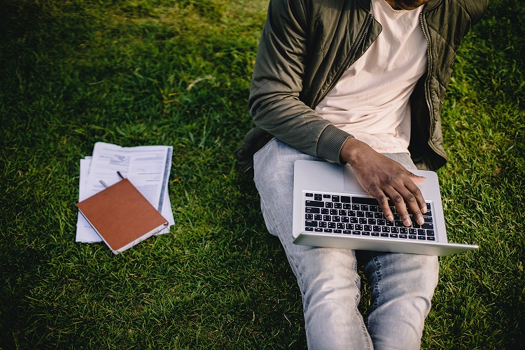 crop-black-student-with-laptop-and-papers-on-green-lawn-4560079.jpg