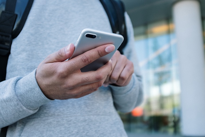 Person in gray long sleeve shirt holding silver iphone